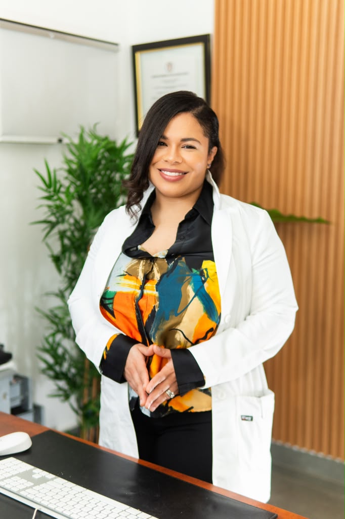 Dr. Bella Acosta Arias in a white coat and colorful blouse, smiling in her office