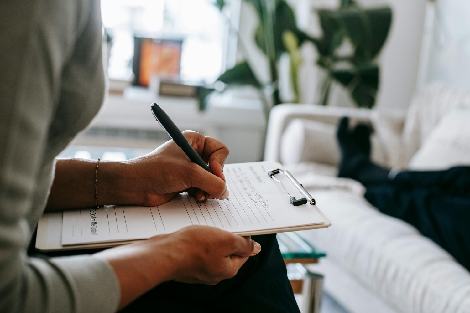 A psychiatrist taking notes on a clipboard during a calm session with a patient