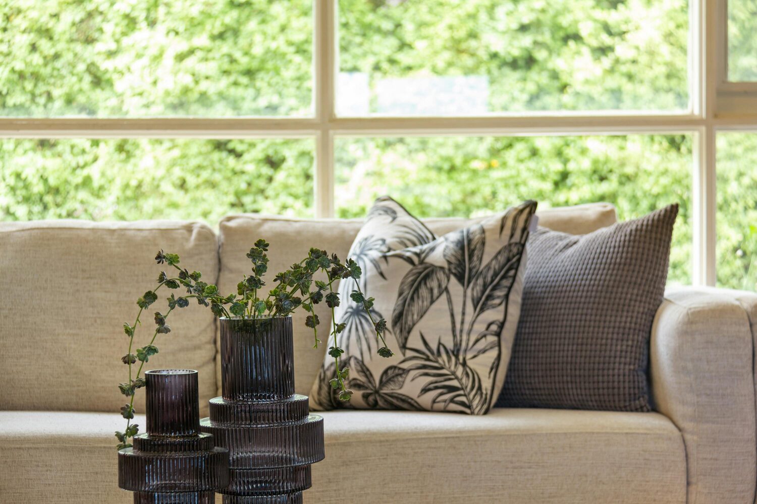 A calm, light-filled living room with soft neutral furnishings and greenery